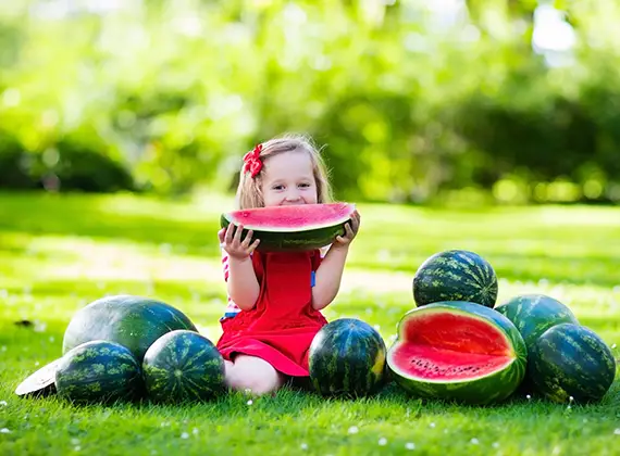 Liten flicka som äter vattenmelon.
