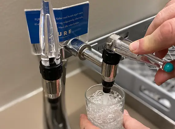 häller soda i glaset.